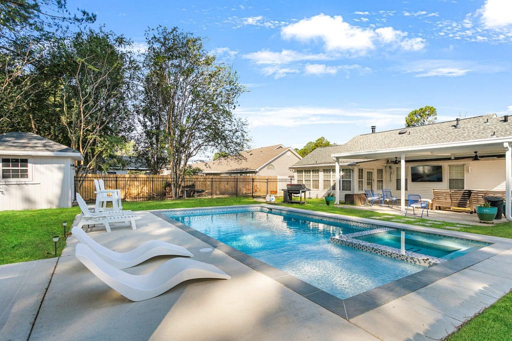 Pool With Lounge And Deck Chairs In The Backyard